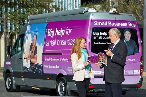 Image of woman talking to man and looking at booklet in front of small business bus